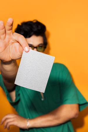 Young man in green shirt holding laundry detergent sheet
