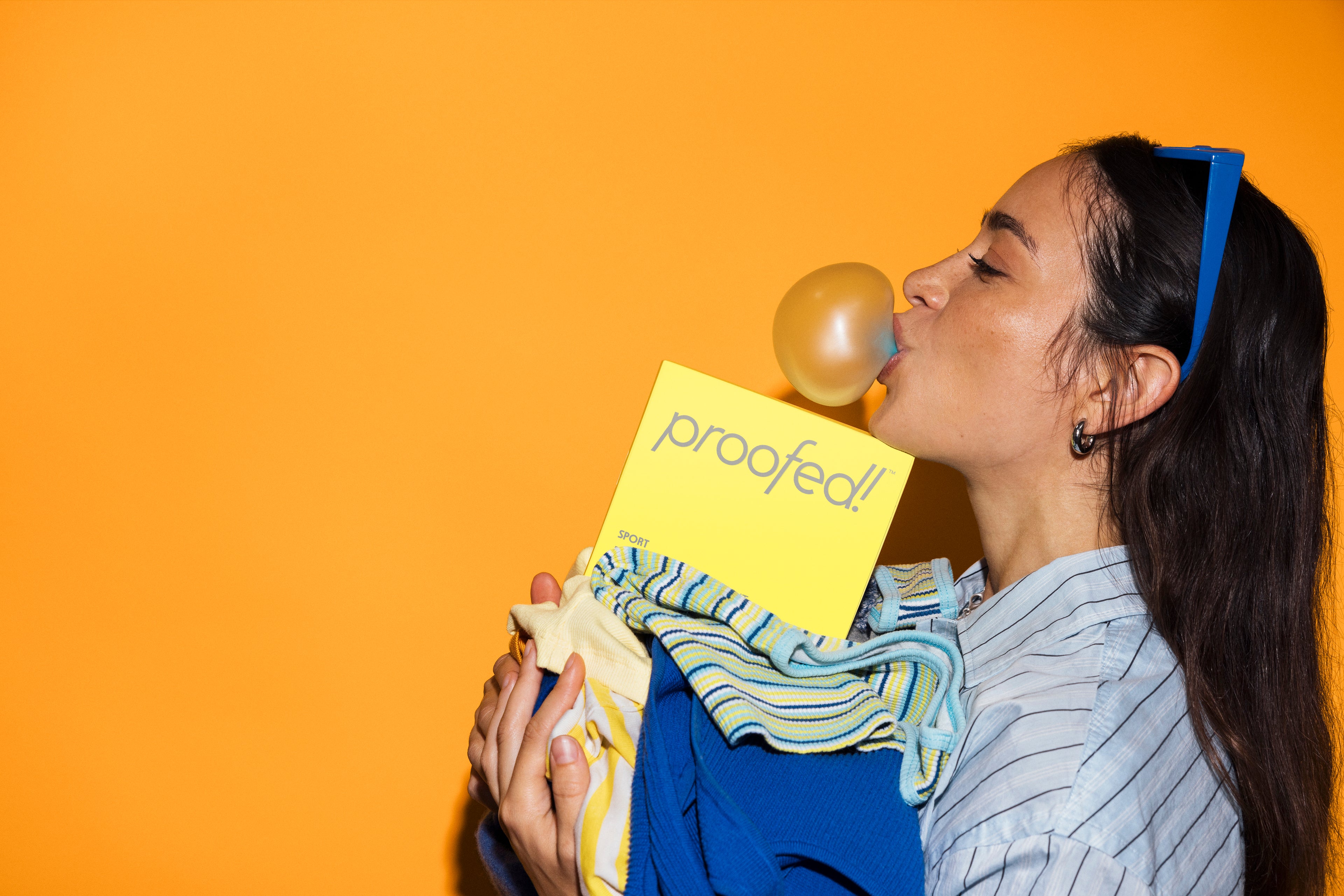 women holding laundry, box of Proofed Laundry sheets and popping bubble gum in mouth